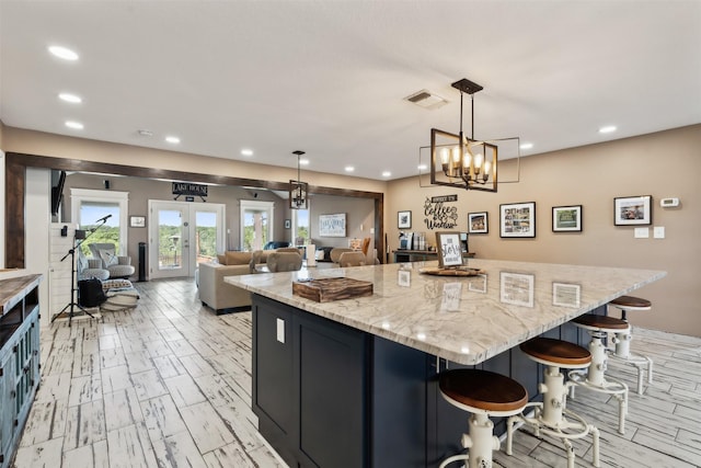 kitchen with visible vents, a center island, light stone countertops, open floor plan, and recessed lighting