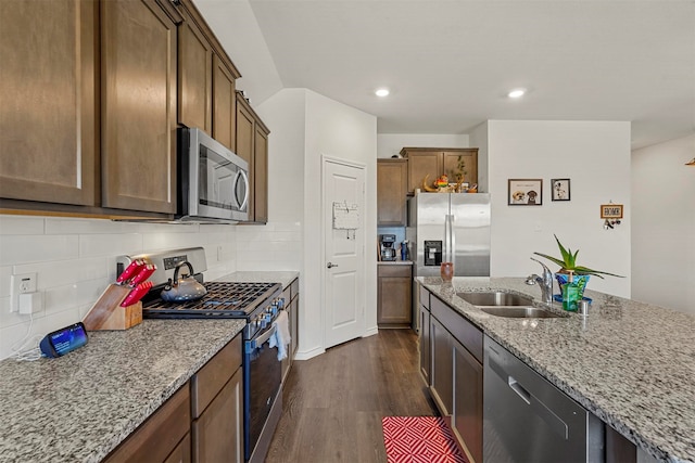 kitchen with dark hardwood / wood-style floors, light stone countertops, backsplash, appliances with stainless steel finishes, and sink