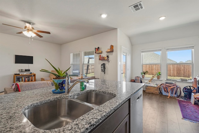 kitchen featuring a healthy amount of sunlight, light stone countertops, sink, wood-type flooring, and stainless steel dishwasher