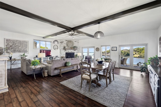 dining room with a large fireplace, beamed ceiling, dark hardwood / wood-style flooring, and ceiling fan