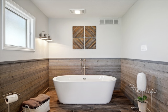 bathroom with a bathtub, tile walls, and hardwood / wood-style floors