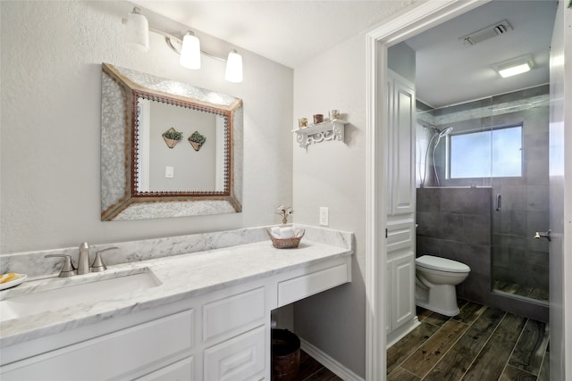 bathroom with a shower with door, hardwood / wood-style floors, vanity, and toilet