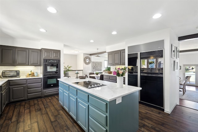 kitchen with black appliances, dark hardwood / wood-style floors, tasteful backsplash, and a center island