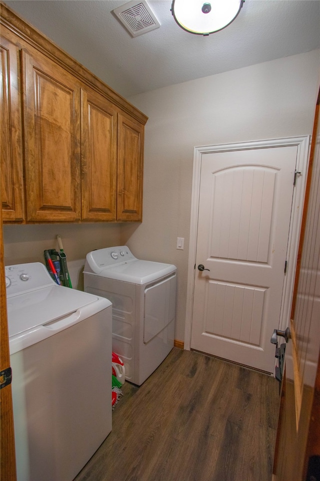 clothes washing area with cabinets, dark hardwood / wood-style floors, and washer and clothes dryer