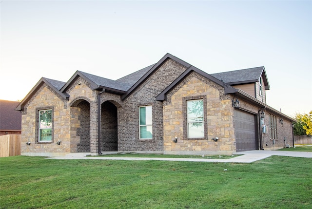 french country home featuring a front lawn and a garage