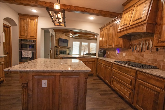 kitchen featuring dark hardwood / wood-style floors, appliances with stainless steel finishes, a center island, and hanging light fixtures