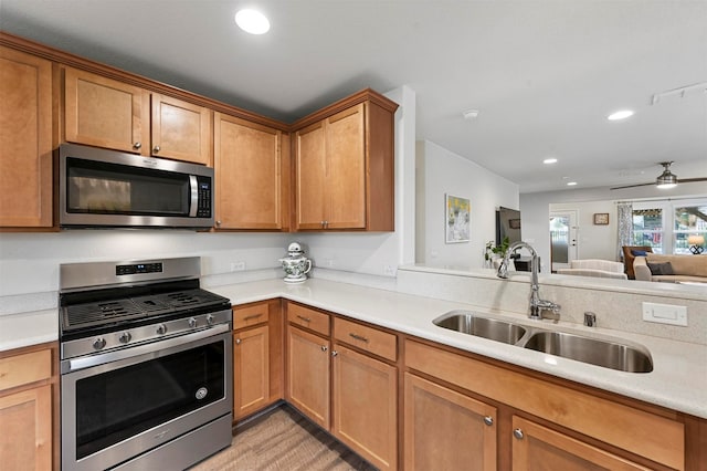 kitchen with appliances with stainless steel finishes, ceiling fan, and sink