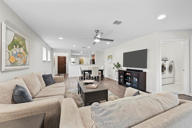 living room with hardwood / wood-style flooring, washing machine and clothes dryer, and ceiling fan