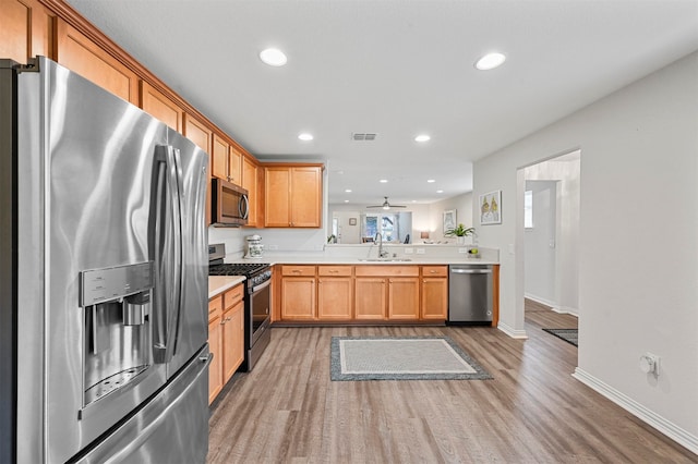 kitchen featuring dark hardwood / wood-style flooring, kitchen peninsula, sink, ceiling fan, and appliances with stainless steel finishes