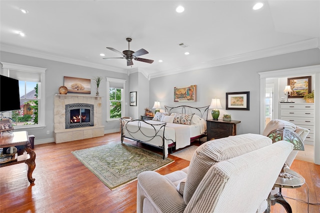 living room with light wood-type flooring, ceiling fan, a wealth of natural light, and a tiled fireplace