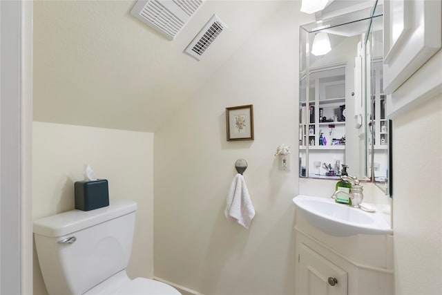 bathroom featuring vanity, toilet, and vaulted ceiling