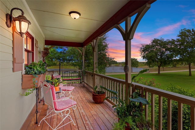 deck at dusk featuring covered porch