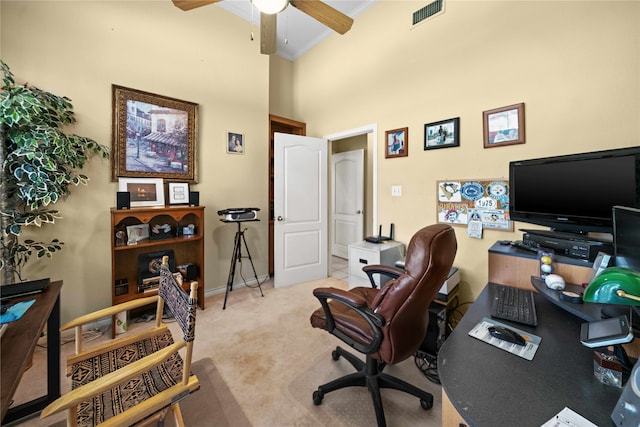 home office featuring crown molding, ceiling fan, light carpet, and a high ceiling