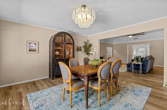 dining room with crown molding, ceiling fan with notable chandelier, and light wood-type flooring