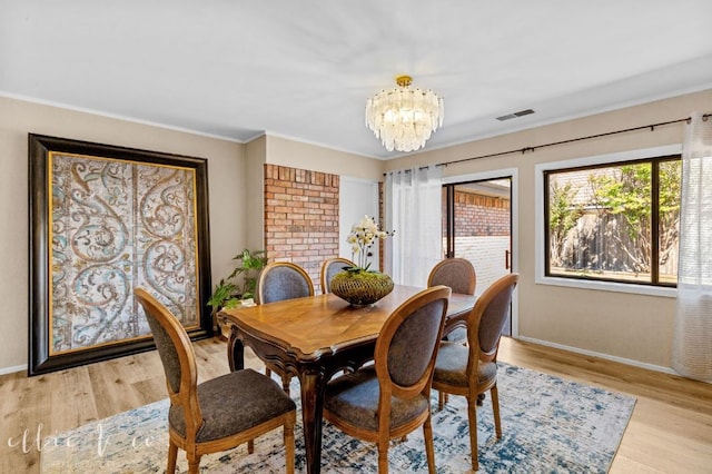 dining room with ornamental molding, a chandelier, and light hardwood / wood-style flooring