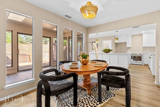 dining space with light wood-type flooring and a notable chandelier