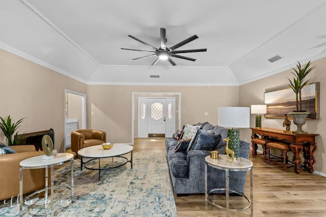 living room with hardwood / wood-style floors, ceiling fan, a raised ceiling, and ornamental molding