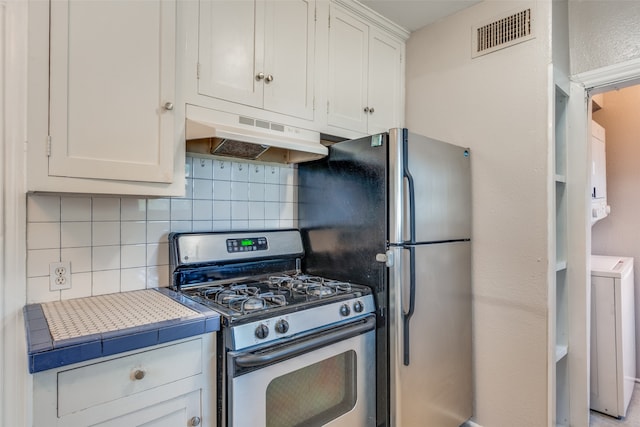 kitchen featuring backsplash, appliances with stainless steel finishes, white cabinetry, washer / dryer, and tile counters