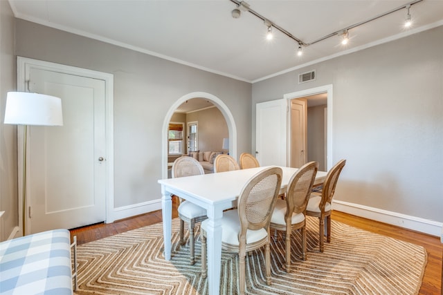 dining space featuring crown molding, rail lighting, and light hardwood / wood-style floors