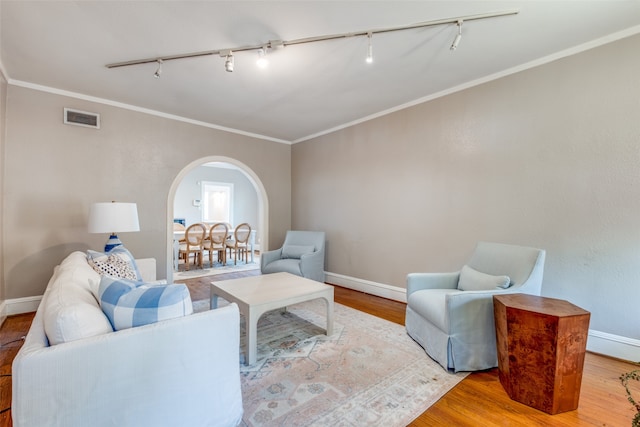 living room with ornamental molding, wood-type flooring, and rail lighting