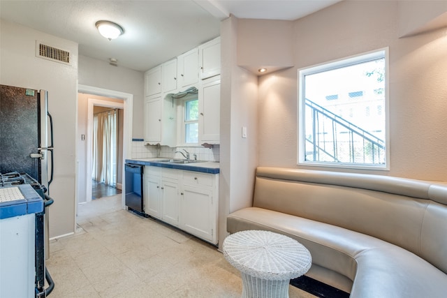 kitchen featuring range, dishwasher, backsplash, and white cabinets