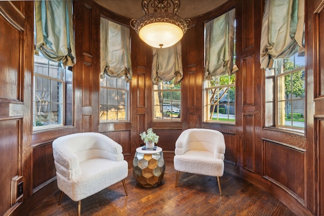 sitting room with wooden walls, dark hardwood / wood-style floors, and a healthy amount of sunlight