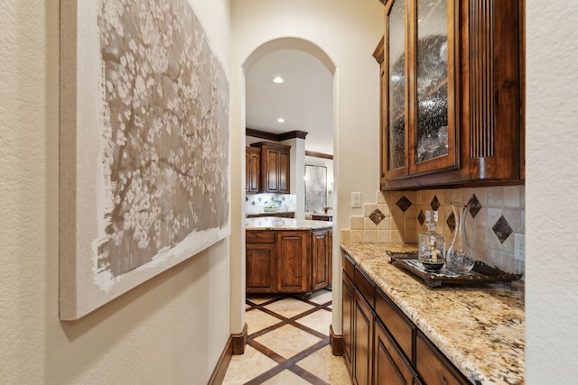 bar featuring light tile patterned floors, light stone counters, and decorative backsplash