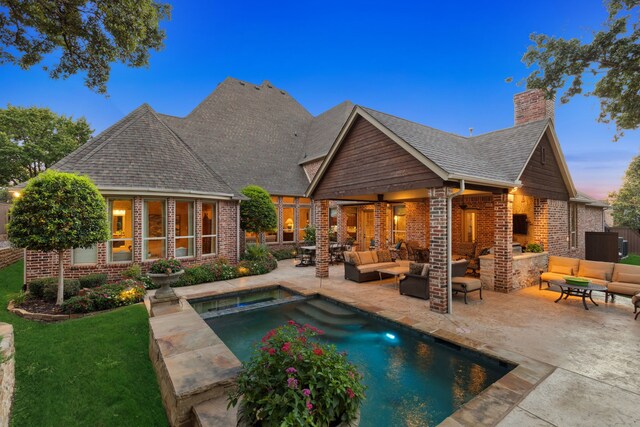 pool at dusk with outdoor lounge area, ceiling fan, and a patio area