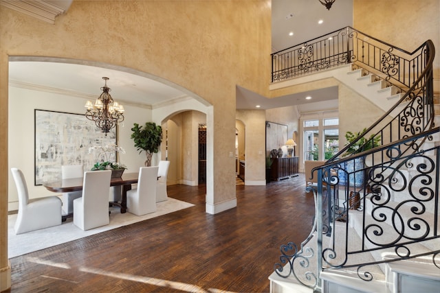 entrance foyer with crown molding, dark hardwood / wood-style floors, a towering ceiling, and a notable chandelier