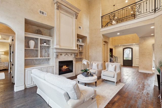 living room with wood-type flooring, a towering ceiling, and built in features