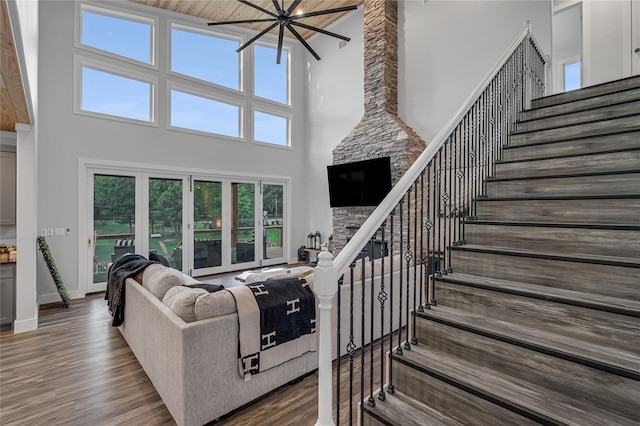 living room featuring a high ceiling, a stone fireplace, and hardwood / wood-style flooring