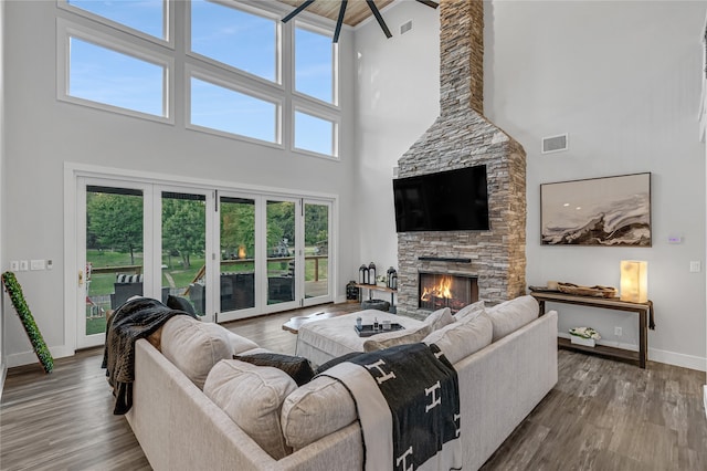 living room with a healthy amount of sunlight, wood-type flooring, and a stone fireplace