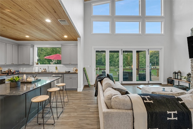 living room with light wood-type flooring, a high ceiling, and sink