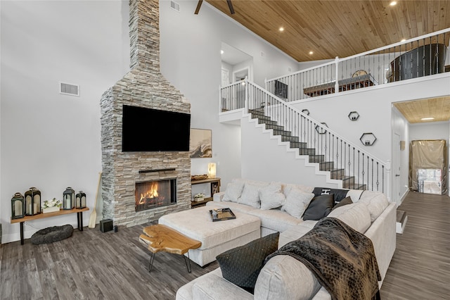 living room with a fireplace, wood ceiling, wood-type flooring, and a high ceiling