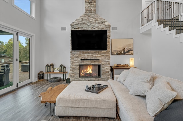 living room with a high ceiling, wood-type flooring, and a fireplace