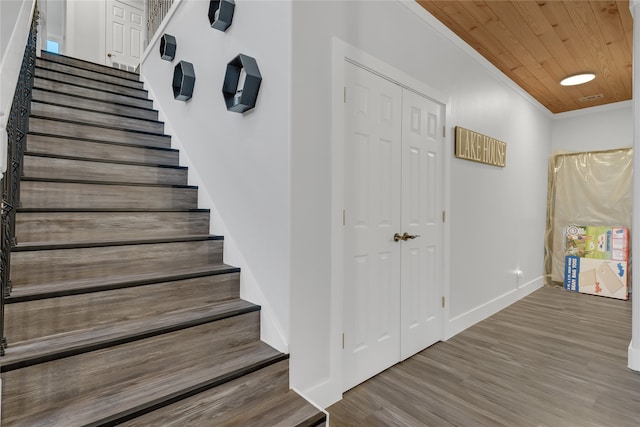 stairway with hardwood / wood-style flooring, ornamental molding, and wooden ceiling