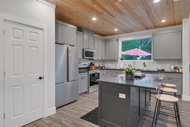 kitchen with appliances with stainless steel finishes, light hardwood / wood-style flooring, a kitchen island, and gray cabinetry