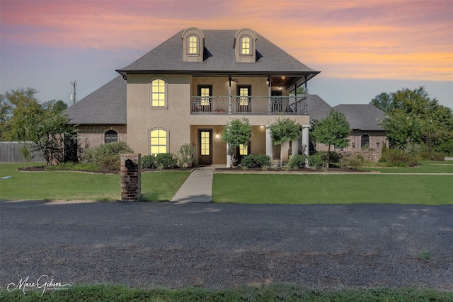 french country inspired facade with a lawn and a balcony