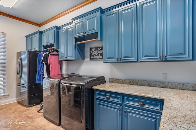 clothes washing area featuring crown molding, washing machine and clothes dryer, and cabinets