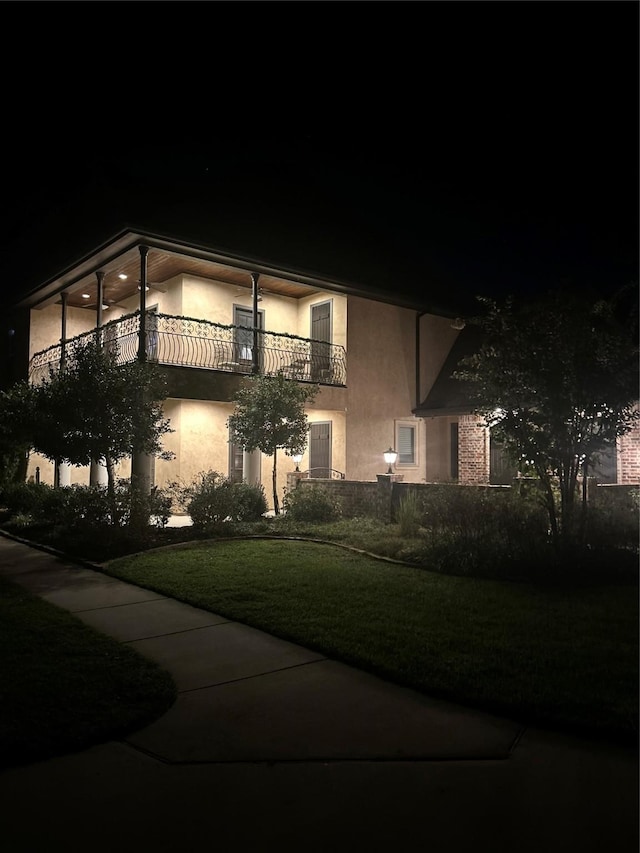 view of front of house with a balcony and a yard