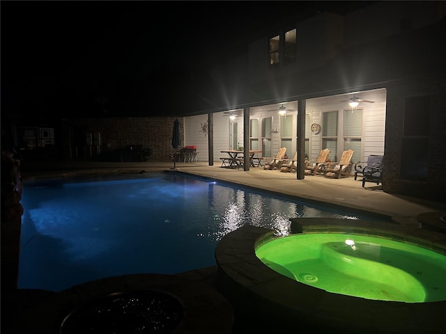 pool at twilight with ceiling fan, a patio area, and an in ground hot tub