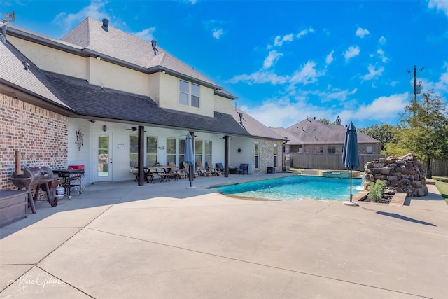 view of swimming pool featuring a pool with connected hot tub, a ceiling fan, fence, and a patio