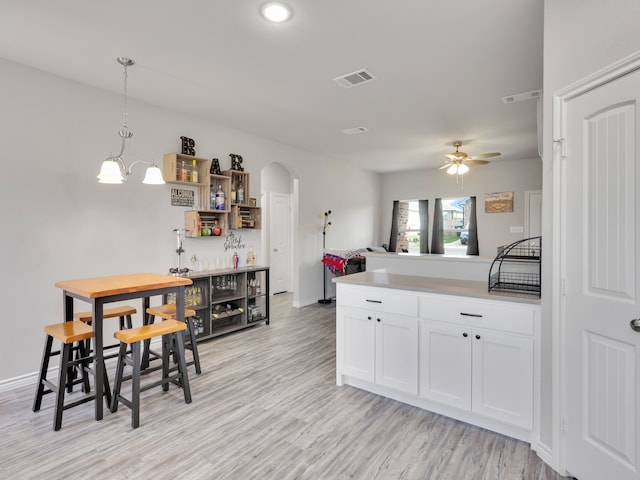 kitchen with ceiling fan with notable chandelier, pendant lighting, light hardwood / wood-style floors, and white cabinetry