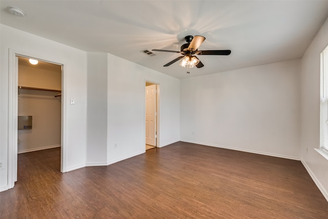 interior space featuring a closet, ceiling fan, a spacious closet, and dark wood-type flooring