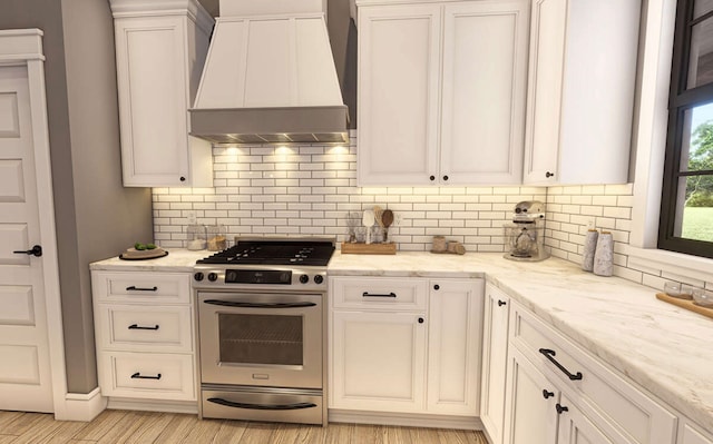 kitchen with high end stainless steel range, light wood-type flooring, white cabinetry, light stone counters, and custom range hood