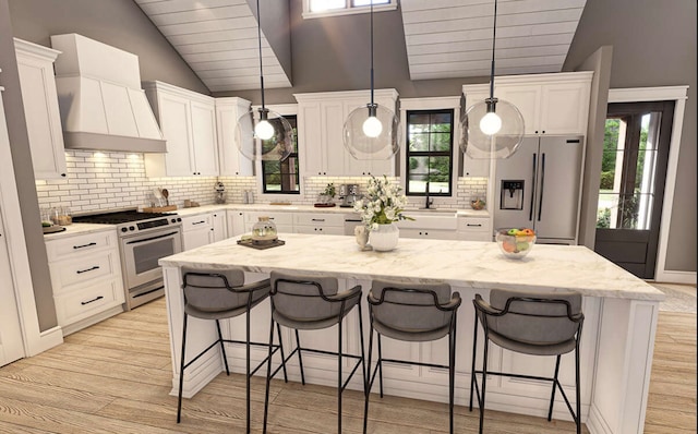 kitchen featuring pendant lighting, stainless steel appliances, plenty of natural light, vaulted ceiling, and white cabinets