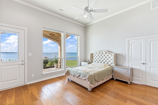 bedroom with a closet, light hardwood / wood-style floors, ornamental molding, ceiling fan, and a water view