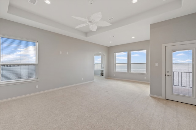 carpeted spare room featuring a tray ceiling and ceiling fan