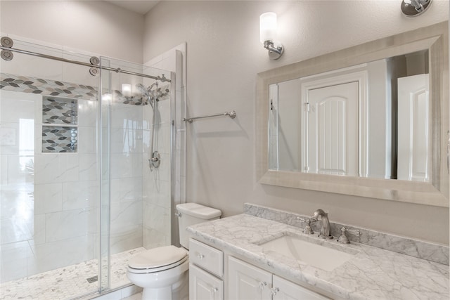 bathroom featuring a shower with shower door, toilet, and vanity