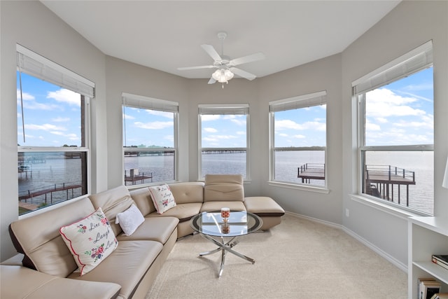 living room featuring light carpet, a water view, and ceiling fan